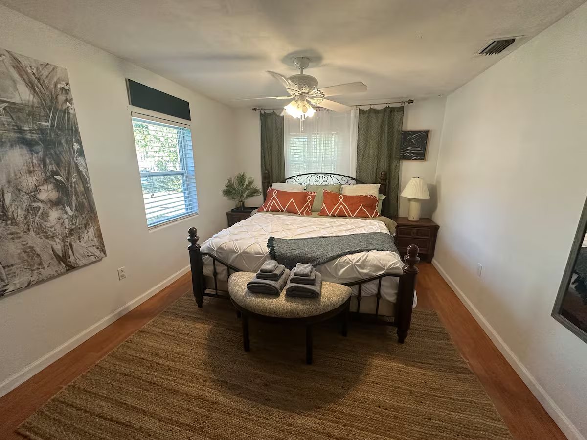 Primary bedroom with king bed, botanical artwork, and soft natural light at Swampy Elegance Retreat
